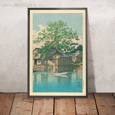 A framed image of River Village with Boatman and Tree by Hasui Kawase, 1935